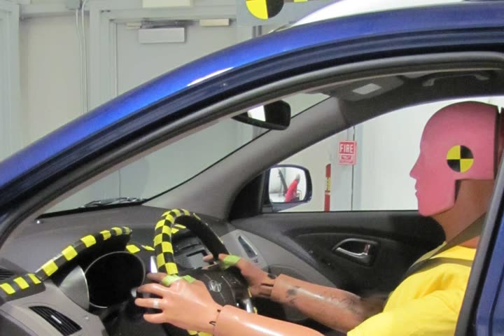 An instrumented crash-test dummy seated at the wheel of a test vehicle